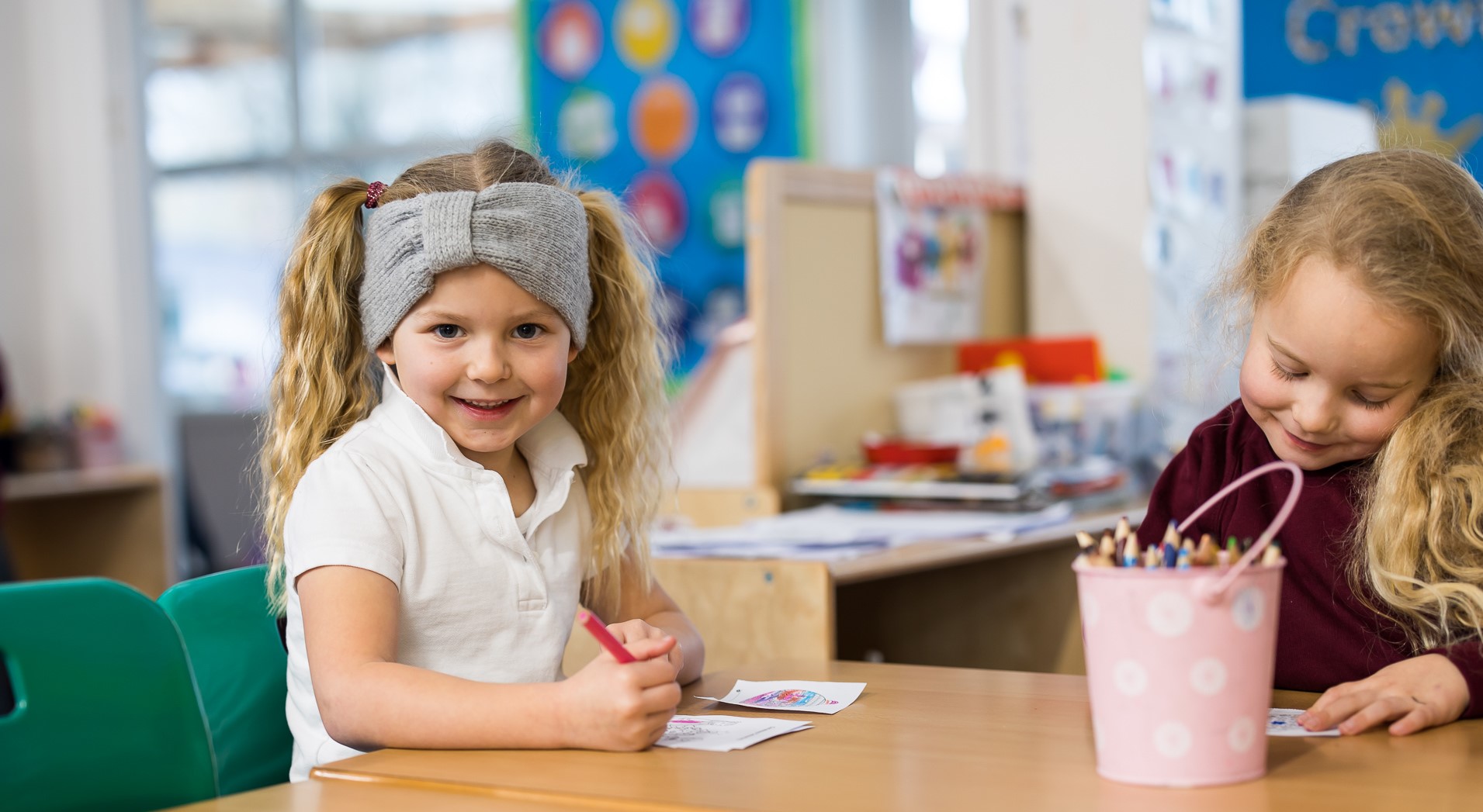 Young girl smiling at the camera while drawing